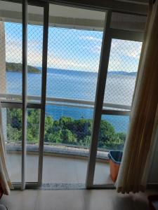 a view of the ocean from a window at Apartamento Aconchegante Porto Real Resort Mangaratiba in Mangaratiba