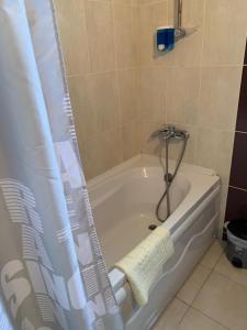 El baño incluye bañera blanca con cortina de ducha. en Luxury Two-Bedroom Apartment in amazing place Lukomorye E5, en Karavas