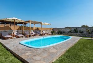 a swimming pool in a yard with chairs and umbrellas at Villa Rose on the beach in Afantou