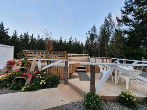 un banco de madera, una mesa y algunas flores en Cabañas Olas del Bosque, en Pichilemu