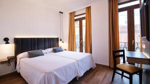 1 dormitorio con 1 cama, escritorio y ventanas en Madrisol, en Madrid