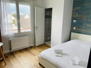 a bedroom with a white bed and a window at Hotel de la Plage in Quinéville