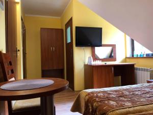 a hotel room with a bed and a table and a tv at Gościnny Dworek in Pobierowo