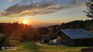 a barn in a field with the sunset in the background at Chalet neuf avec jacuzzi privé, vue imprenable sur Massif des Vosges in Belfahy