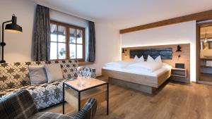 um quarto de hotel com uma cama e um sofá em Wohlfühlhotel Berwanger Hof em Obermaiselstein