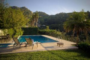 Ein Kind sitzt auf Stühlen neben einem Schwimmbecken in der Unterkunft Casa do Valle in Sintra