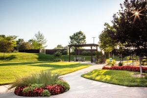 a park with a bench and flowers in the grass at Holiday Inn Wichita East I-35 by IHG in Wichita