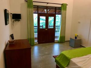 a bedroom with a bed and a door with green curtains at Talalla Leisure in Talalla
