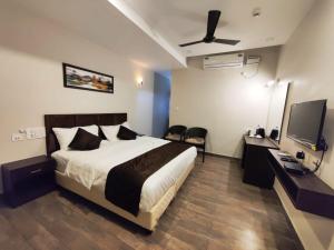 een slaapkamer met een bed, een bureau en een televisie bij HOTEL PARK KRISHNA in Tirupati