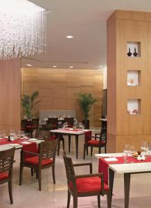 a restaurant with tables and chairs and a chandelier at Trident Chennai in Chennai