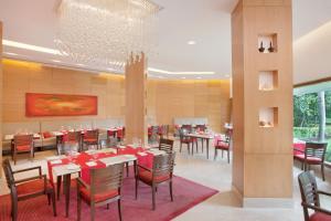 a dining room with tables and chairs and a chandelier at Trident Chennai in Chennai