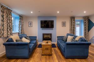 a living room with two blue couches and a fireplace at Clwyd Cottage - Two Bed, Barn Conversion with Private Hot Tub in Bodfari
