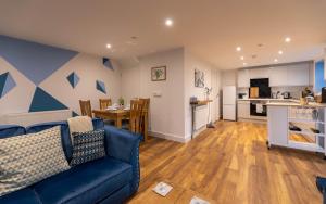 a living room with a blue couch and a kitchen at Clwyd Cottage - Two Bed, Barn Conversion with Private Hot Tub in Bodfari
