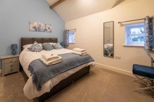 a bedroom with a large bed and a mirror at Clwyd Cottage - Two Bed, Barn Conversion with Private Hot Tub in Bodfari