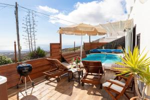 un patio con piscina, sillas y sombrilla en Finca La Casita, en La Asomada