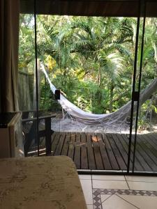 a hammock in a room with a view of a deck at Vila da Pousadinha in Ilha do Mel