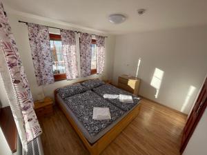 a small bedroom with a bed and two windows at Apartmany215 in Strážné