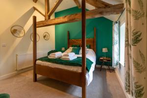 1 dormitorio con cama con dosel y paredes verdes en Dyffryn Cottage - King bed, self-catering cottage with Hot Tub en Denbigh