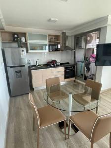 cocina con mesa de cristal, sillas y nevera en Place Lafayette Espectacular Vista Piso 19, 1 Dorm, Amenities, en Punta del Este