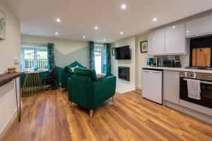 a living room with a green couch and a kitchen at Dyffryn Cottage - King bed, self-catering cottage with Hot Tub in Denbigh