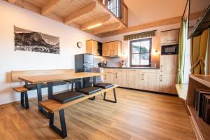 a kitchen and dining room with a wooden table and benches at Chalets und Apartments Hauserhof Nassfeld in Schlanitzen
