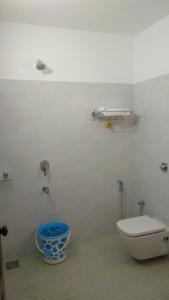 a bathroom with a toilet and a blue bucket at Vibgyor Villa in Munnar
