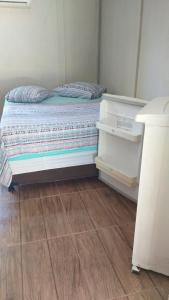 a small bedroom with a bed and a wooden floor at Pousada Margareth in Ilha do Mel