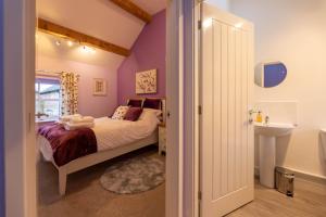 - une chambre avec des murs violets, un lit et un lavabo dans l'établissement Blodyn Cottage - Cosy, Self-Catering with Private Hot Tub, à Bodfari