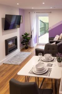 a living room with a white table and a fireplace at Blodyn Cottage - Cosy, Self-Catering with Private Hot Tub in Bodfari