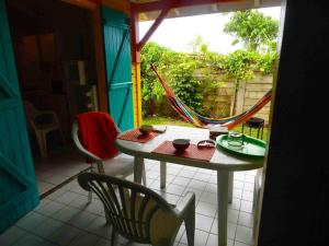 a patio with a table and chairs and a hammock at Maison Charme Sainte-Rose in Sainte-Rose