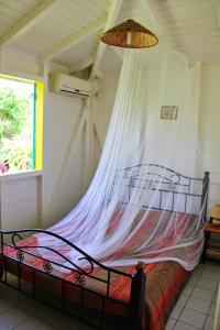a bedroom with a bed with a mosquito net at Maison Charme Sainte-Rose in Sainte-Rose