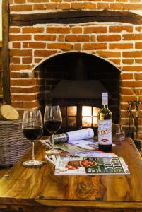 a table with two glasses of wine and a brick fireplace at Lavender Cottage in Thorndon