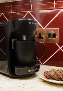 a coffee maker on a counter next to a plate of cookies at Lavender Cottage in Thorndon