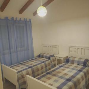 2 camas en una habitación con ventana en 2 bedrooms house with furnished terrace and wifi at Pescia Romana 3 km away from the beach, en Pescia Romana