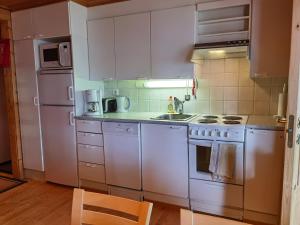 a kitchen with white appliances and a wooden floor at Kuerkömmeli, Äkäslompolo in Äkäslompolo