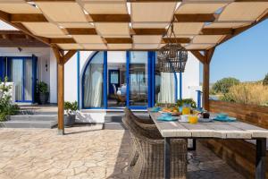 a patio with a table and chairs under a pergola at Villa Rose on the beach in Afantou