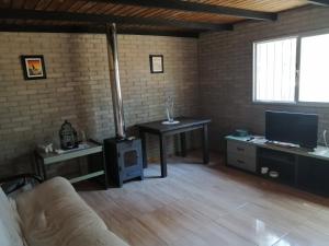 ein Wohnzimmer mit einem Sofa, einem Tisch und einem TV in der Unterkunft Casa en Jaureguiberry a 5 cuadras de la playa in Jaureguiberry