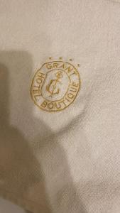 a gold embroidered logo on a white shirt at Grant Apartament in Arad