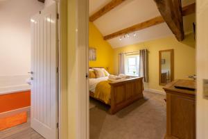 une chambre avec un lit aux murs jaunes et une fenêtre dans l'établissement Caer Fedwen Barns Heulog Cottage King Bed Self Catering with Private Hot Tub, à Bodfari