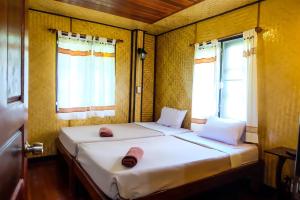 twee bedden in een kleine kamer met twee ramen bij Baansuan Lychee Maeklong Resort Ampawa in Amphawa