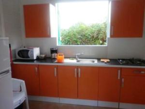 a kitchen with orange cabinets and a sink and a window at Maison charmante à Sainte-Rose, piscine. in Sainte-Rose