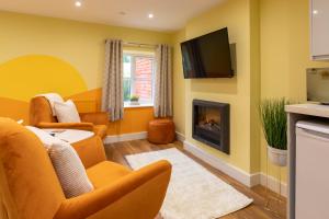 a living room with yellow walls and a fireplace at Heulog Cottage - King Bed, Self-Catering with Private Hot Tub in Bodfari