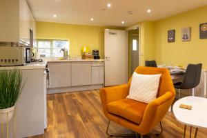 une cuisine avec une chaise orange et une table dans l'établissement Caer Fedwen Barns Heulog Cottage King Bed Self Catering with Private Hot Tub, à Bodfari 8 autres photos