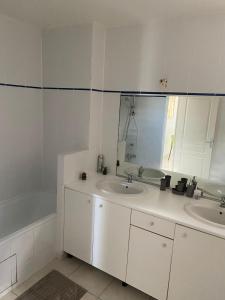ein Badezimmer mit zwei Waschbecken, einer Badewanne und einem Spiegel in der Unterkunft Bas de villa , Résidence Venus calme, vue sur mer in La Trinité