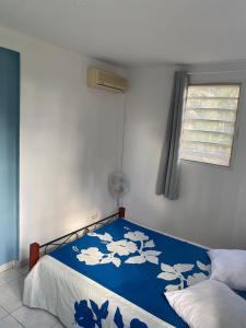 Schlafzimmer mit einem Bett mit blauer und weißer Bettwäsche in der Unterkunft Bas de villa , Résidence Venus calme, vue sur mer in La Trinité