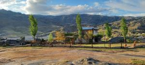 a house in the mountains with a fence and trees at CASAS VIEJAS LODGE in La Cumbrecita
