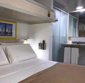 a bedroom with a white bed and a kitchen at Expresso R1 Hotel Economy Suites in Maceió