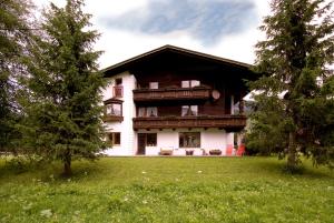 ein großes Haus auf einem Feld mit einem Baum in der Unterkunft Apartments Tannheim in Tannheim