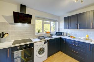 una cucina con armadi blu e lavatrice di Inspire Homes 2-Bed Sleeps 5 near Leamington & M40 a Southam