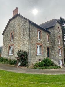 an old stone building on a field of grass at Les hortensias in Grand-Fougeray